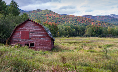 Old run down barn with fall color in the Adirondacks in the background