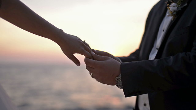 The groom inserting a solitaire into the bride's finger.