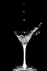 Cocktail glass with splashes isolated on a black background.