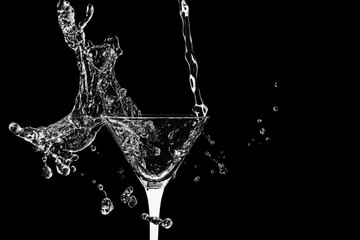 Cocktail glass with splashes isolated on a black background.