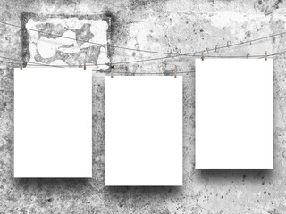 Three empty frames hanged by clothespin on grey concrete wall background