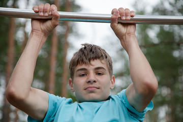 The teenager doing exercise on a horizontal bar