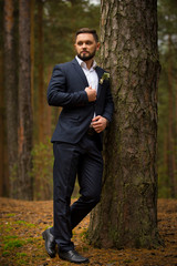 groom with a beard waiting for a tree