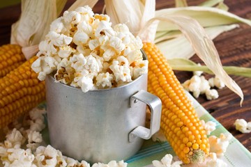 Old cup with popcorn and few corncobs