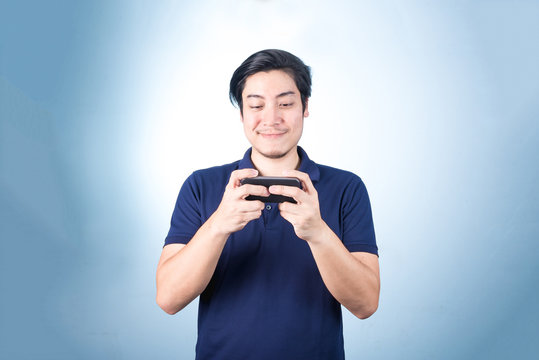 Asian guy with mobile phone in hand, on blue background