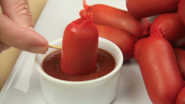 Australian frankfurter called a cheerio on a toothpick being dipped into ketchup.