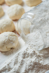 Small balls of fresh homemade dough on floured wooden board