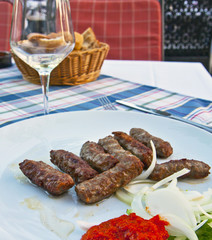 Cevapcici - Balkanic plate, grilled meatballs of different kind of meat mixed toghether with garlic, served with raw onions and a paprika dressing