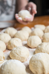 Small balls of fresh homemade dough on floured wooden board