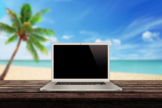 white laptop on the table with a beach palm tree and sea in the background mockup presentation