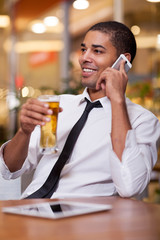 relaxed businessman in a restaurant drinking beer and talking on