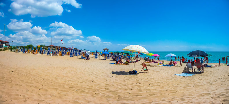 Beautiful vacation beach with beach chairs and sun shades on a sunny day at Lido di Metaponto, Basilicata, Italy