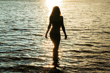dark silhouette woman at sunset in water