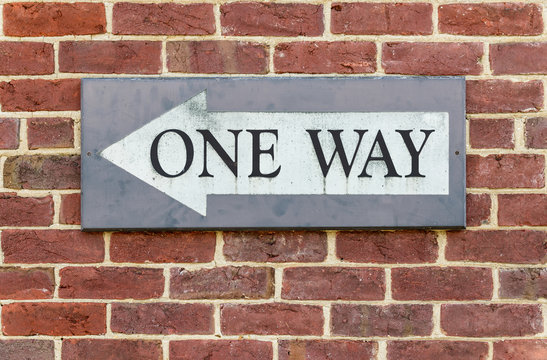 One way sign on a brick wall