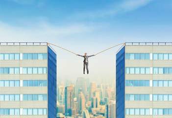 Businesswoman hanging between two skyscrapers 