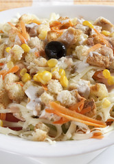 Delicious salad of fresh vegetables with ham, cheese and egg, served in a white bowl.