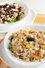 Delicious salad of fresh vegetables with ham, cheese and egg, served in a white bowl.