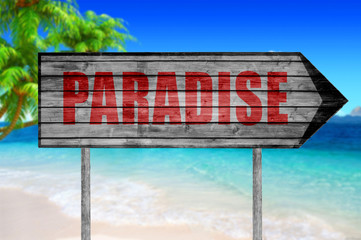 Red Paradise wooden sign with on a beach background