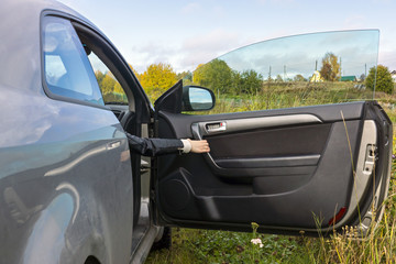 Fototapeta na wymiar Human hand opens the car door In the countryside