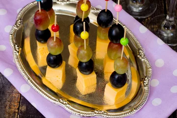 Deurstickers Canape with cheese and grapes on a wooden table © elena_hramowa