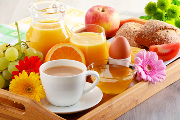 Breakfast on tray served with coffee, juice, egg, and rolls