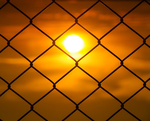 Fototapeta premium Mesh fence with the sun set
