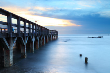 Obraz premium Wooden bridge into the sea at sunset