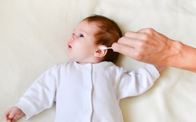 hand is cleaning baby's ear