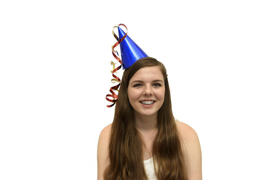 Party Girl. Smiling, Young Woman Wearing A Blue Party Hat With Red And Gold Streamers Isolated On A White Background