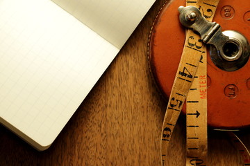 Vintage background viewed from above. Old measuring tape, notebook and equipment.