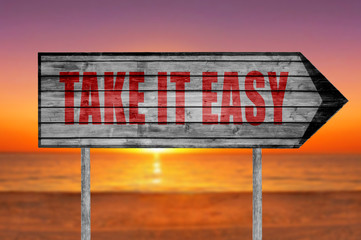 Red Take It Easy wooden sign with on a beach background