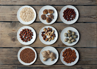 Different products on saucers on wooden table, top view