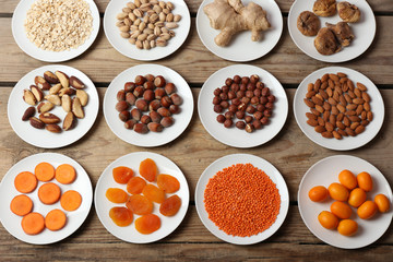 Different products on saucers on wooden table, top view