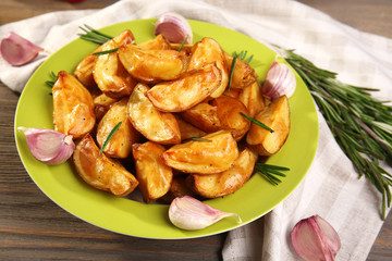 Baked potato wedges on wooden table, closeup