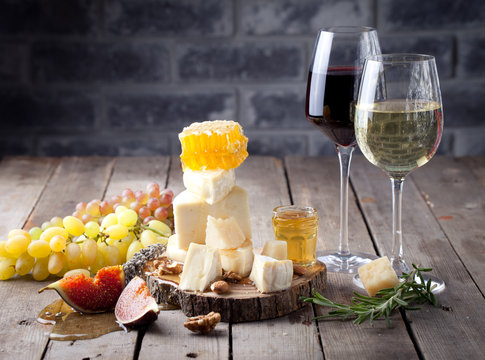 Cheese plate with honey, grape, wine in glasses