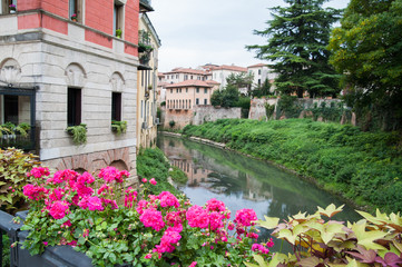 Fototapeta na wymiar Flowered vase of geraniums in the balcony of San Paolo bridge and the old stone San Michele bridge in the background
