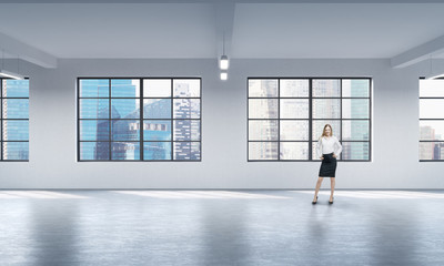 Fototapeta premium Front view of a full length woman in formal clothes who stands in a modern loft open space. Singapore panoramic view.