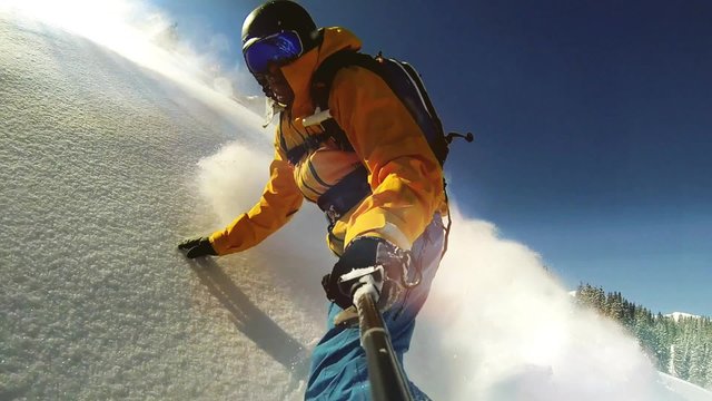 Man riding on snowboard with selfie stick in his hand , slow motion shot