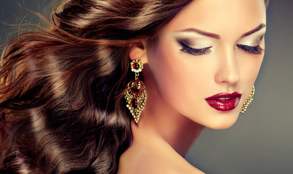 Fototapeta Beautiful model with curly hair and large earrings . fashion trend image ,the girl with blue eyes , fashion makeup and    earrings jewelry