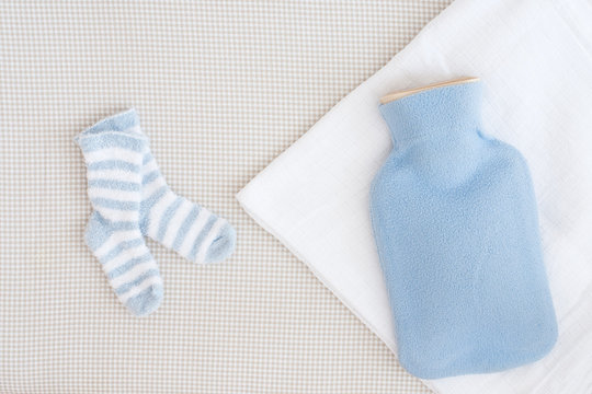 Hot Water Bottle And Little Baby Socks - Studio Shot From Above