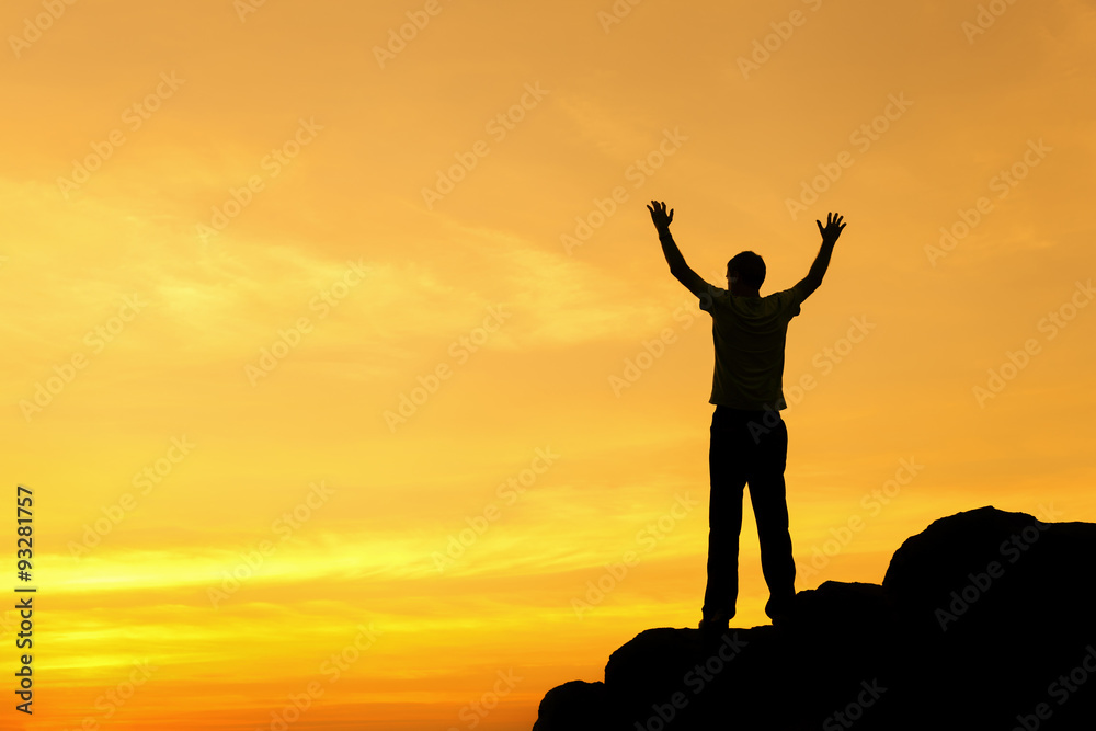 Wall mural silhouette of a man with raised-up arms at the sunset