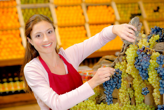 Shop assistant making display with grapes