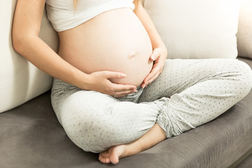 pregnant woman sitting on couch and holding tummy