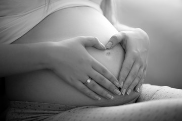 black and white photo of pregnant caring mother touching belly