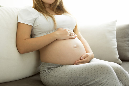caring pregnant mother relaxing on sofa at living room