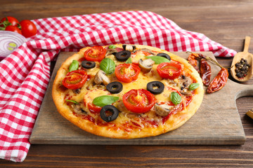 Tasty pizza with vegetables and basil on table close up