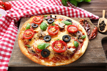 Tasty pizza with vegetables and basil on table close up
