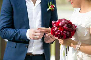 Obraz na płótnie Canvas Closeup of young groom putting wedding ring on bride's finger