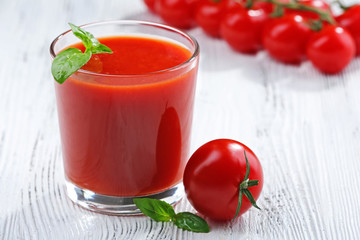 Glass of tomato juice on wooden background