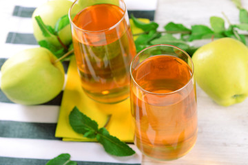 Glasses of apple juice with fruits and fresh mint on table close up